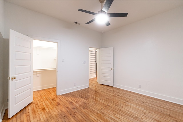 unfurnished bedroom with ceiling fan, a closet, a spacious closet, and light hardwood / wood-style flooring