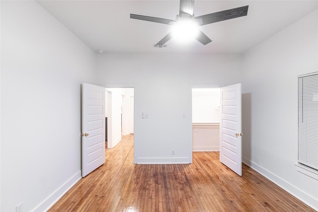 unfurnished bedroom featuring a spacious closet, light hardwood / wood-style flooring, a closet, and ceiling fan