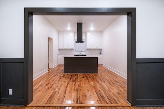 kitchen with white cabinetry, sink, extractor fan, and light wood-type flooring