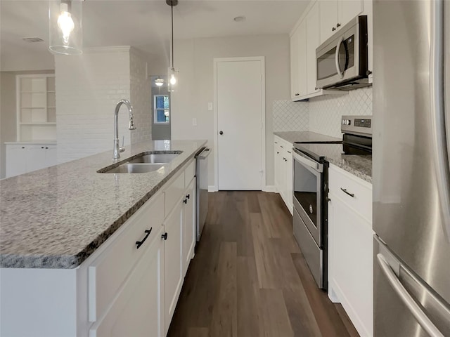 kitchen with a kitchen island with sink, sink, decorative light fixtures, and stainless steel appliances