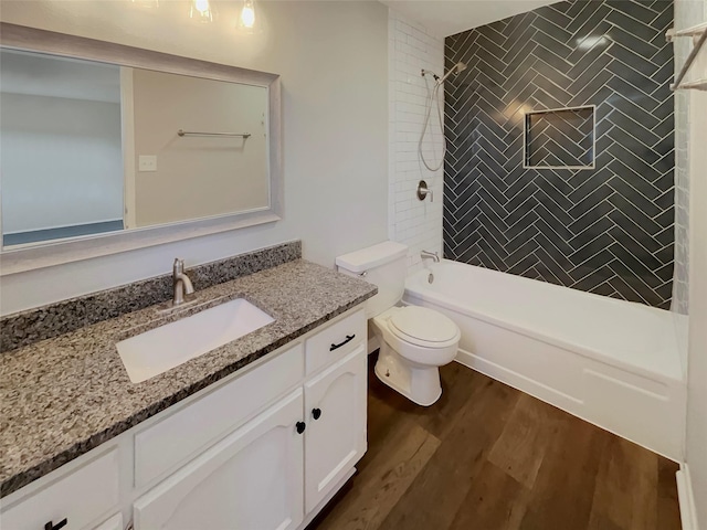 full bathroom featuring hardwood / wood-style flooring, tiled shower / bath, vanity, and toilet