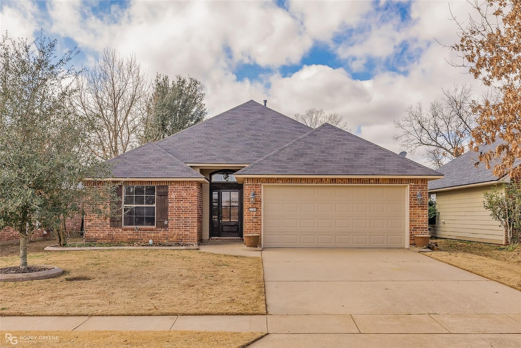 ranch-style house featuring a garage and a front lawn