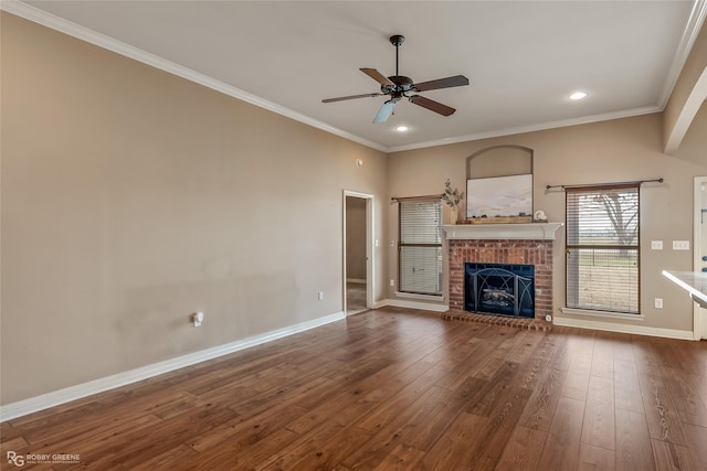 unfurnished living room featuring a brick fireplace, hardwood / wood-style flooring, ornamental molding, and ceiling fan