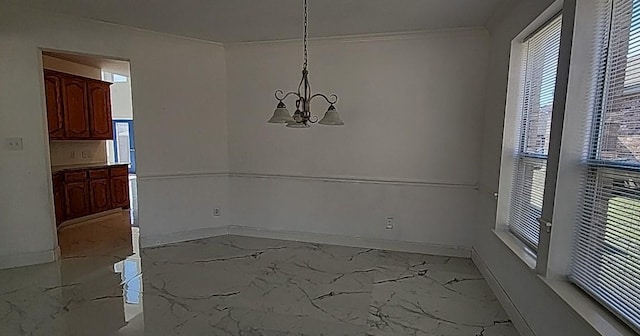 unfurnished dining area featuring crown molding and a chandelier