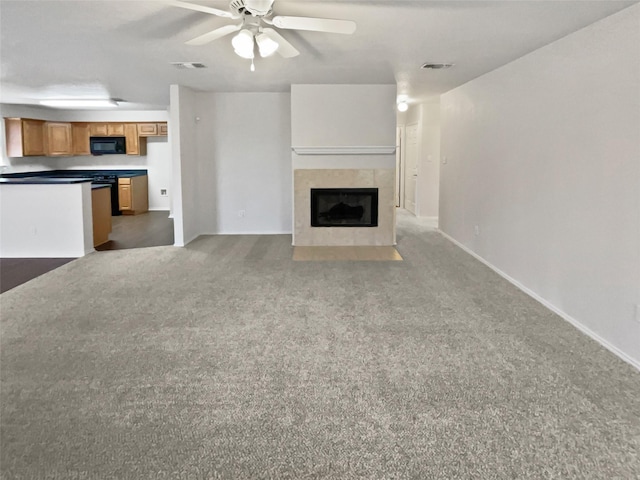 unfurnished living room featuring a tiled fireplace, carpet flooring, and ceiling fan