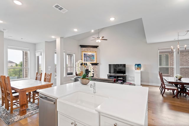 kitchen featuring a sink, visible vents, white cabinetry, open floor plan, and dishwasher