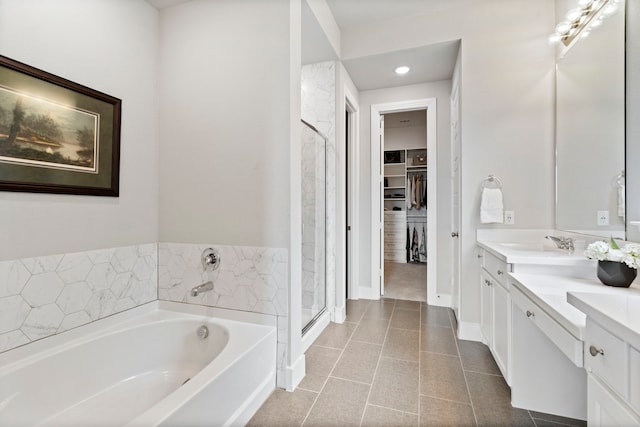 full bathroom with double vanity, a stall shower, baseboards, a walk in closet, and a bath