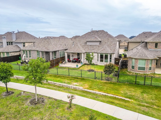 view of front of property featuring a patio, a front lawn, a fenced backyard, and brick siding