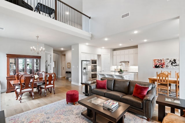 living room with light wood-style floors, a chandelier, visible vents, and baseboards