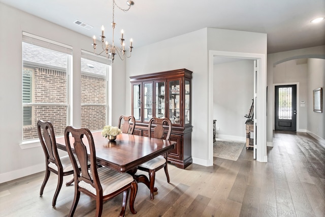 dining area with hardwood / wood-style flooring, baseboards, visible vents, and arched walkways