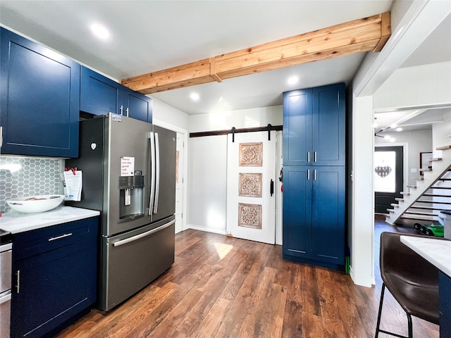 kitchen with dark wood-type flooring, stainless steel refrigerator with ice dispenser, blue cabinets, a barn door, and beamed ceiling