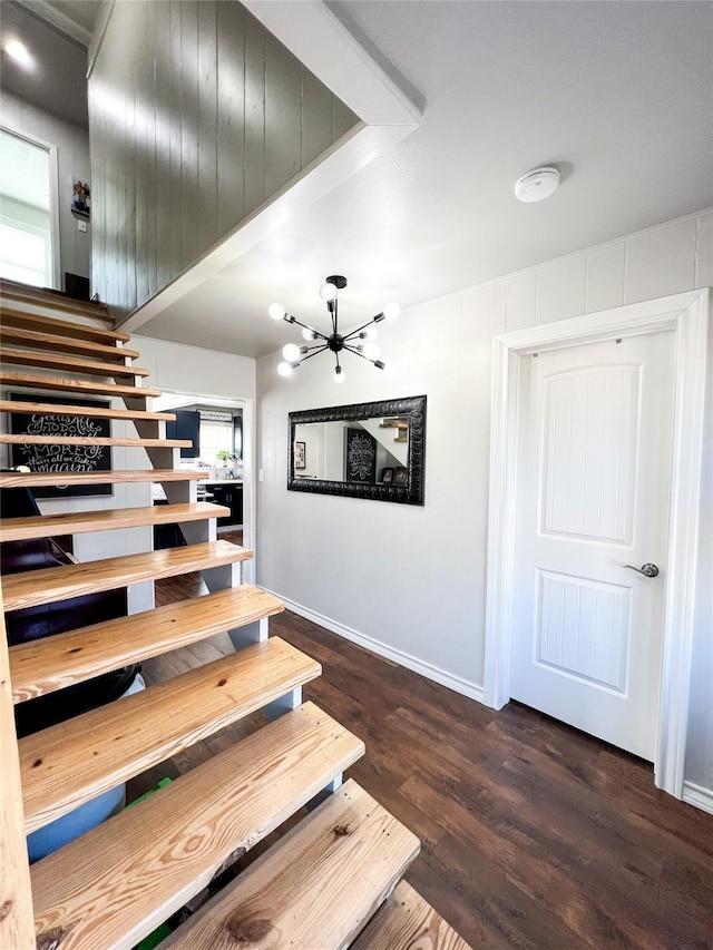 stairs featuring wood-type flooring and a notable chandelier