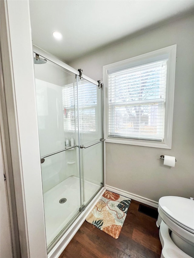 bathroom featuring a shower with door, wood-type flooring, and toilet