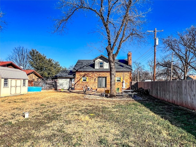 back of house with a storage unit and a yard