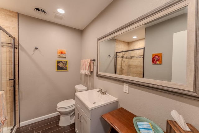 bathroom featuring hardwood / wood-style flooring, vanity, toilet, and a shower with shower door