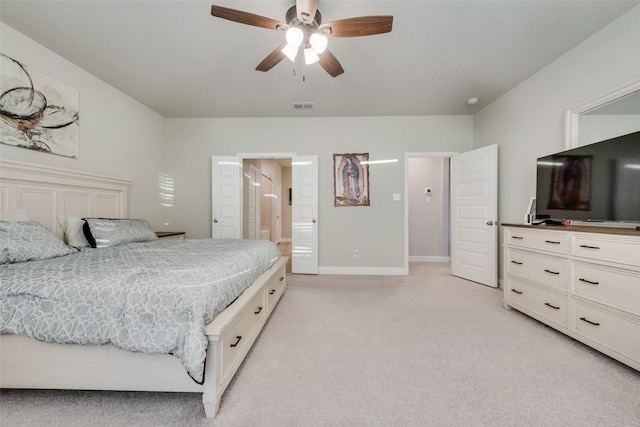 bedroom with light carpet, ensuite bath, and ceiling fan