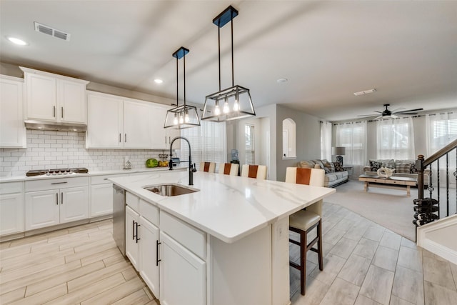 kitchen featuring sink, stainless steel appliances, an island with sink, white cabinets, and decorative light fixtures