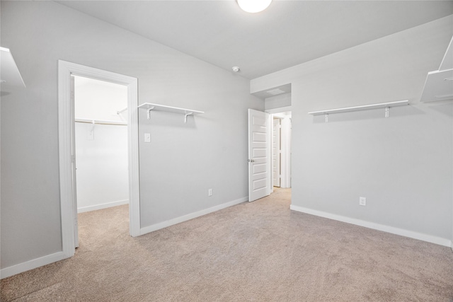 unfurnished bedroom with light carpet, a spacious closet, and a closet