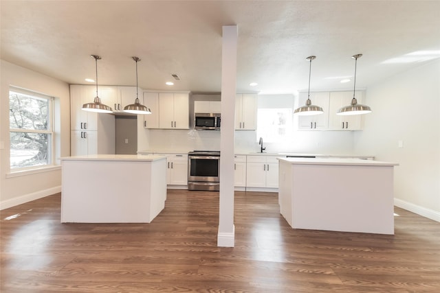 kitchen with sink, white cabinetry, appliances with stainless steel finishes, a kitchen island, and pendant lighting