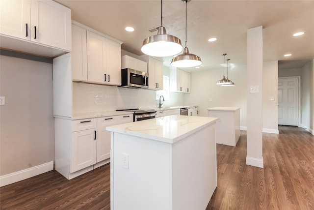 kitchen featuring dark wood-type flooring, white cabinetry, hanging light fixtures, stainless steel appliances, and a kitchen island