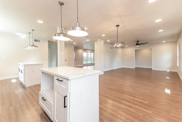 kitchen with decorative light fixtures, white cabinetry, a center island, ceiling fan, and light wood-type flooring