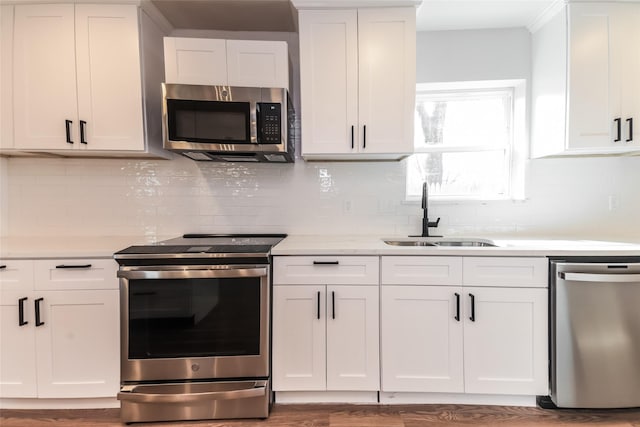 kitchen with dark wood-type flooring, sink, white cabinetry, stainless steel appliances, and backsplash