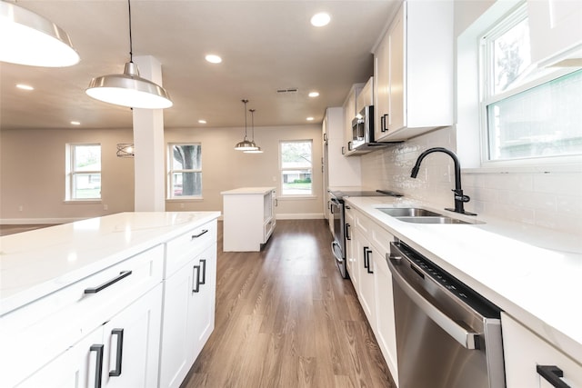 kitchen featuring stainless steel appliances, sink, hanging light fixtures, and white cabinets