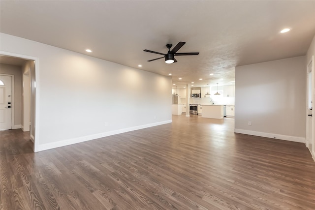 unfurnished living room with dark hardwood / wood-style floors, sink, and ceiling fan