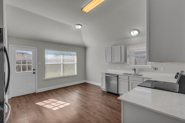 kitchen featuring vaulted ceiling, appliances with stainless steel finishes, sink, light stone counters, and dark wood-type flooring