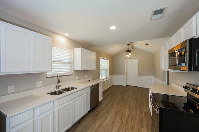 kitchen with appliances with stainless steel finishes, pendant lighting, white cabinetry, lofted ceiling, and sink