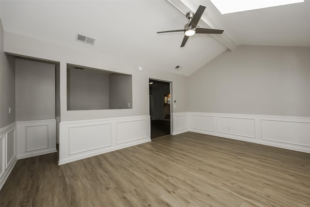 spare room featuring hardwood / wood-style flooring, ceiling fan, and lofted ceiling with skylight