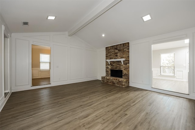 unfurnished living room featuring hardwood / wood-style flooring, plenty of natural light, a fireplace, and vaulted ceiling with beams