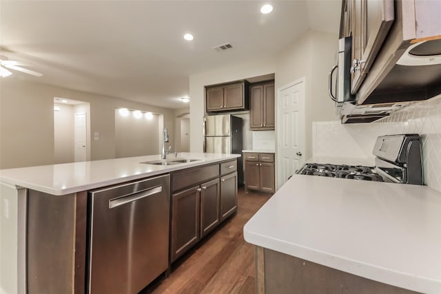 kitchen featuring dark brown cabinetry, sink, a center island with sink, appliances with stainless steel finishes, and decorative backsplash