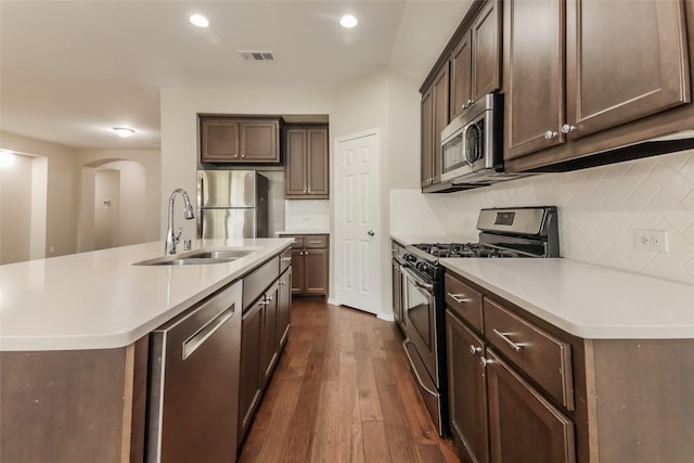 kitchen featuring appliances with stainless steel finishes, dark hardwood / wood-style floors, sink, and a center island with sink