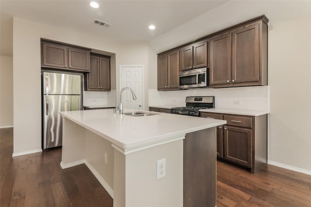 kitchen featuring an island with sink, stainless steel appliances, sink, and dark brown cabinets