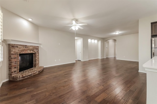 unfurnished living room featuring dark hardwood / wood-style flooring, ceiling fan, and a fireplace