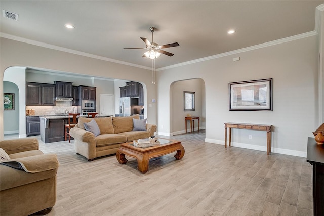 living room with light hardwood / wood-style flooring, ornamental molding, and ceiling fan