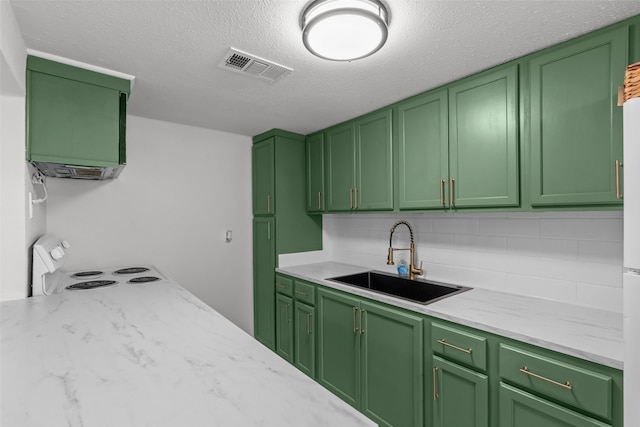 kitchen with tasteful backsplash, stove, sink, and green cabinets