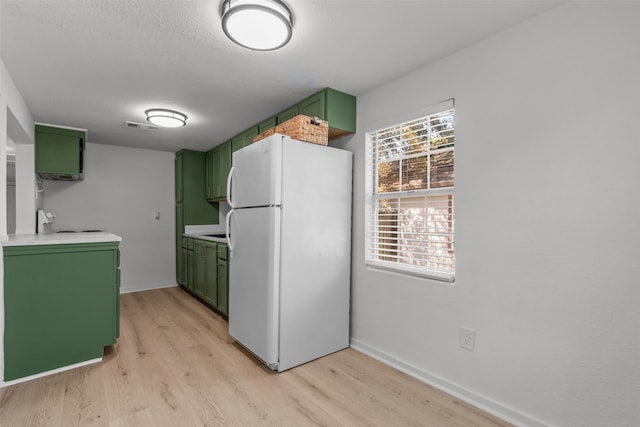 kitchen featuring range, white refrigerator, a textured ceiling, green cabinetry, and light wood-type flooring