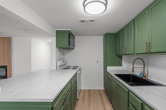 kitchen with white range with electric cooktop, sink, backsplash, green cabinetry, and light hardwood / wood-style flooring