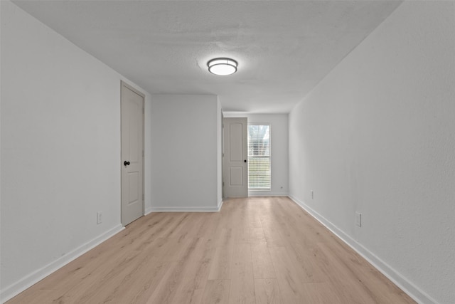 spare room featuring a textured ceiling and light hardwood / wood-style flooring