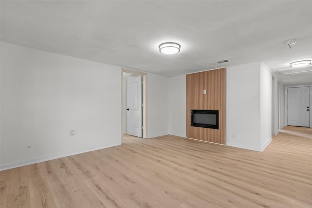 unfurnished living room featuring a large fireplace and light hardwood / wood-style flooring