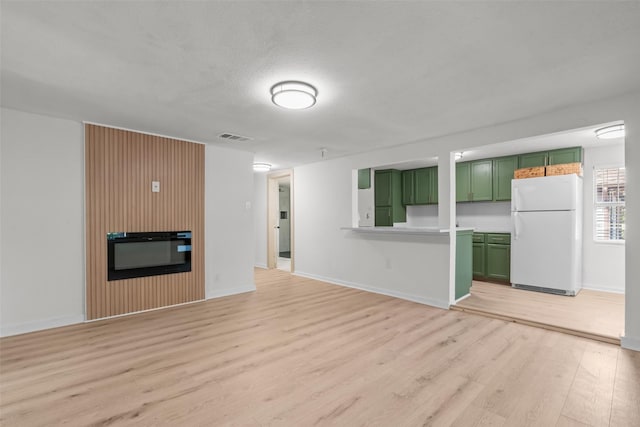 unfurnished living room with a fireplace, a textured ceiling, and light wood-type flooring