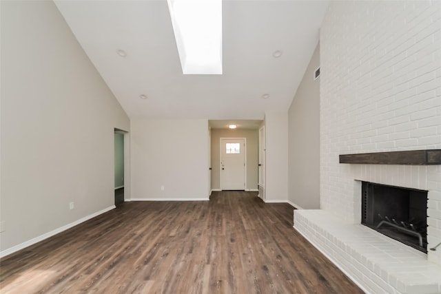 unfurnished living room featuring a brick fireplace, high vaulted ceiling, dark hardwood / wood-style flooring, and a skylight