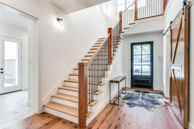 entrance foyer featuring a high ceiling, a barn door, and light wood-type flooring