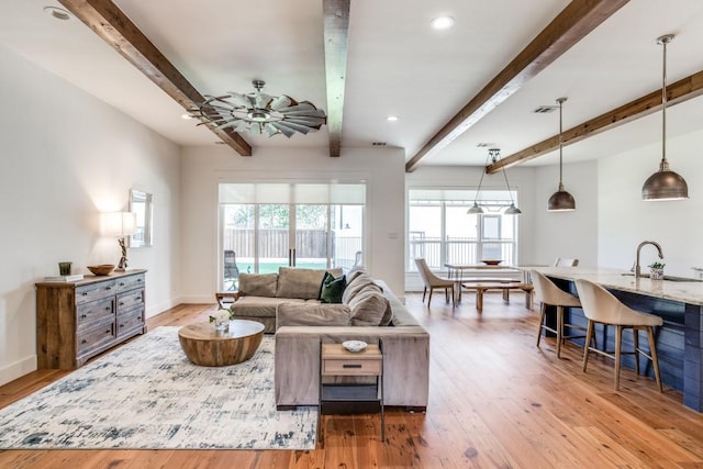 living room featuring hardwood / wood-style flooring, ceiling fan, beam ceiling, and sink