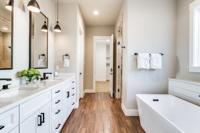 bathroom with hardwood / wood-style flooring, vanity, and a tub