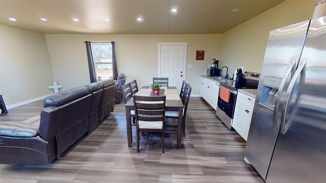 kitchen featuring sink, appliances with stainless steel finishes, white cabinetry, light stone counters, and wood-type flooring