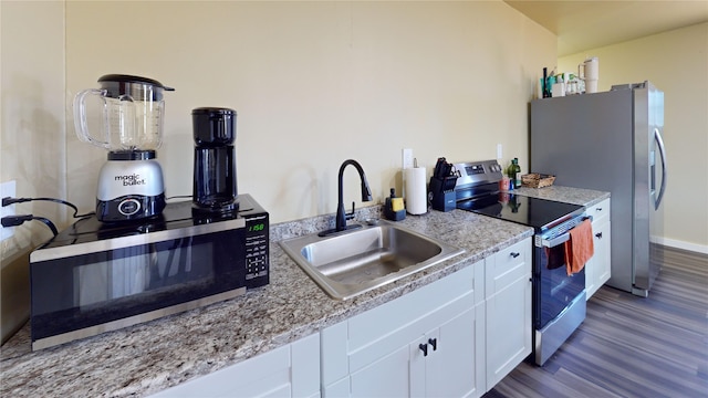 kitchen with white cabinetry, sink, light stone counters, and stainless steel appliances