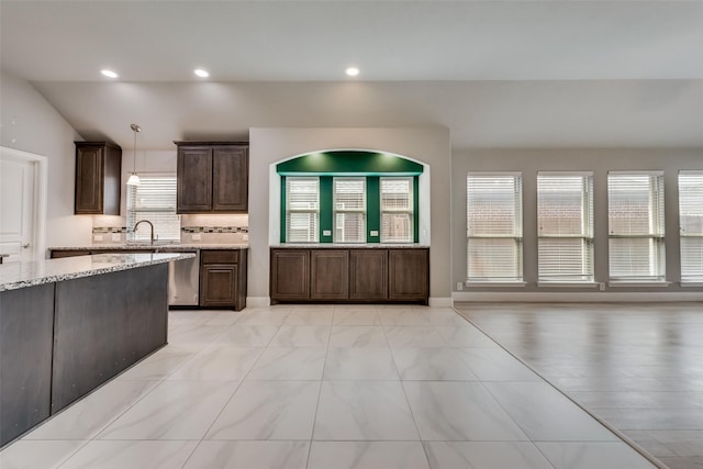 kitchen with dishwasher, decorative backsplash, hanging light fixtures, dark brown cabinetry, and light stone counters